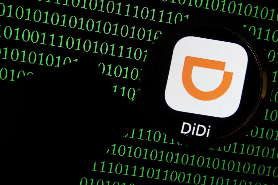 The app logo of Chinese ride-hailing giant Didi is seen through a magnifying glass on a computer screen showing binary digits in this illustration picture taken 7 July 2021. (Florence Lo/Illustration/File Photo/Reuters)