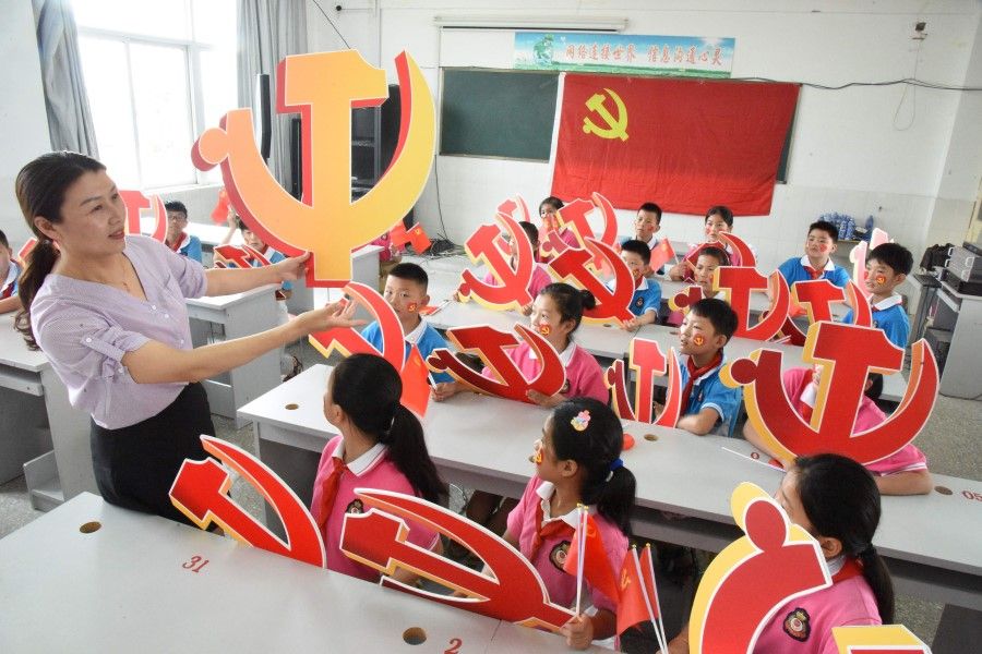 A teacher and her students pose with Communist Party emblems during a class about the history of the Communist Party at a school in Lianyungang, in China's eastern Jiangsu province, 28 June 2020. (STR/AFP)