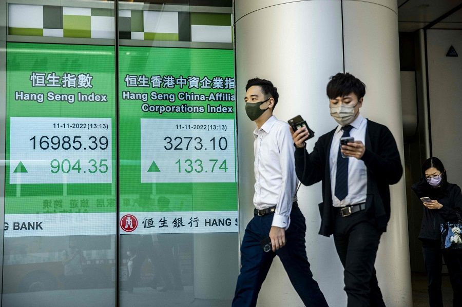 People walk past an electronic sign showing numbers of the Hang Seng Index in Hong Kong, China, on 11 November 2022. (Isaac Lawrence/AFP)