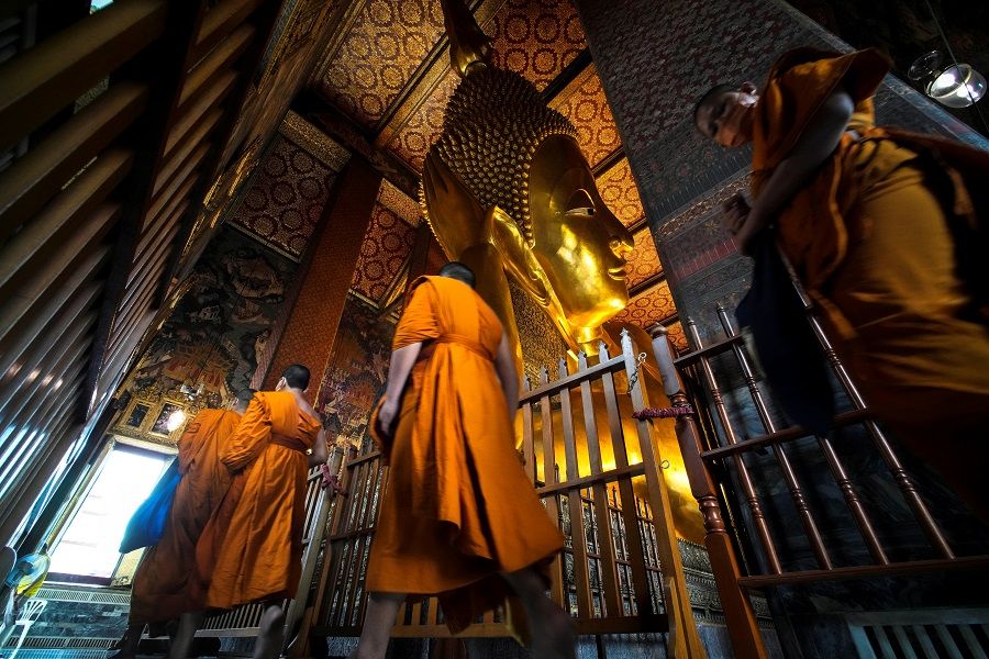Buddhist monks are seen next to the Reclining Buddha at Wat Pho in Bangkok, Thailand, 2 November 2021. (Athit Perawongmetha/Reuters)