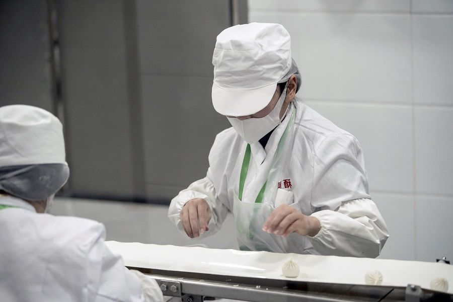 An employee wearing a protective mask works on the dumpling production line at a Hi-Su Food Co. factory in Shanghai, China, on 1 April 2020. Chinese officials emphasised that China's food processing procedures are not affected by the Covid-19 pandemic. (Qilai Shen/Bloomberg)
