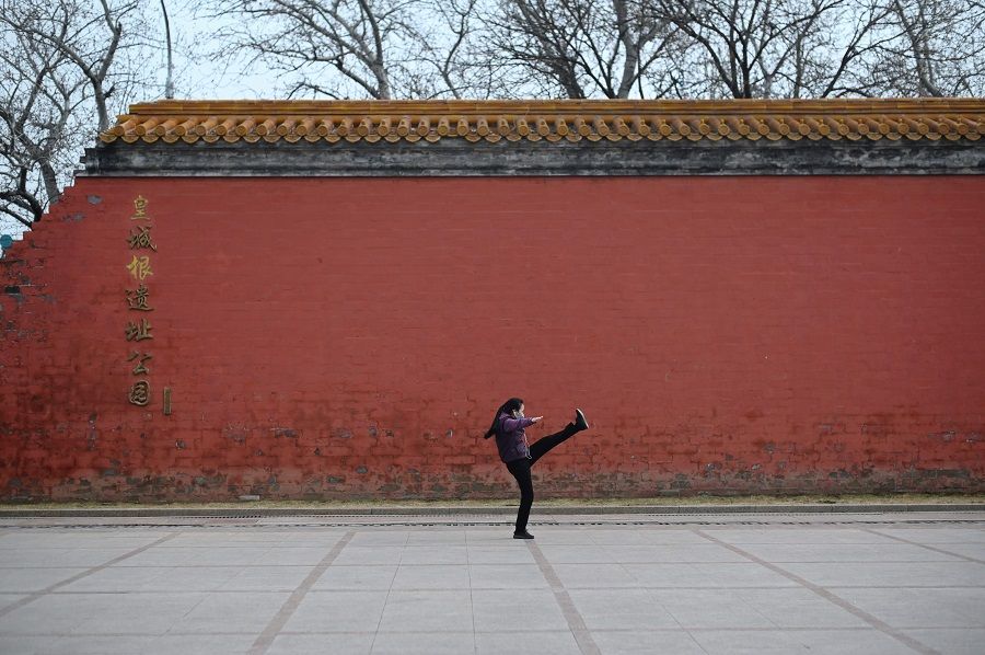 This picture taken on 21 February 2020 shows a woman wearing a face mask, amid concerns of the Covid-19 coronavirus, exercising at a park in Beijing. (Wang Zhao/AFP)