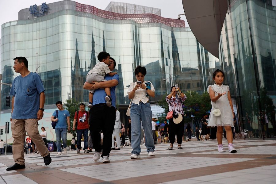 People walk at a shopping area in Beijing, China, 5 September 2023. (Tingshu Wang/Reuters)