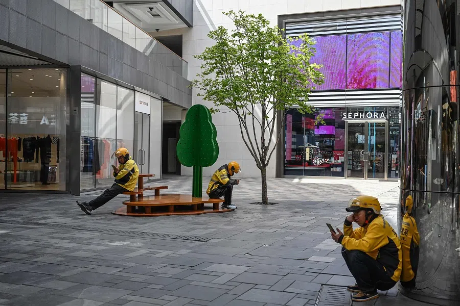 Food delivery drivers rest at a shopping mall complex in Beijing, China on 15 April 2024. (Jade Gao/AFP)