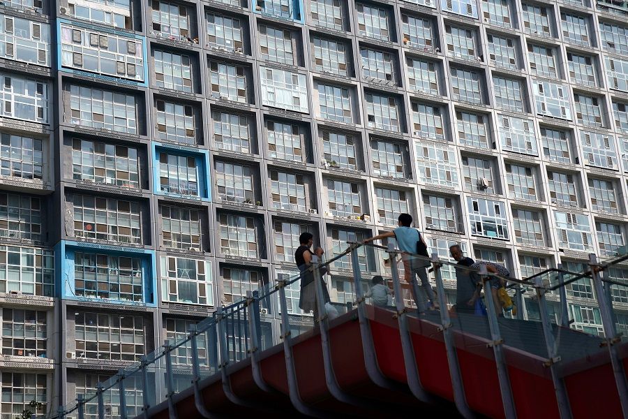 People wearing face masks are seen on an overpass in front of a residential building in Beijing, China, 11 August 2020. (Tingshu Wang/File Photo/Reuters)