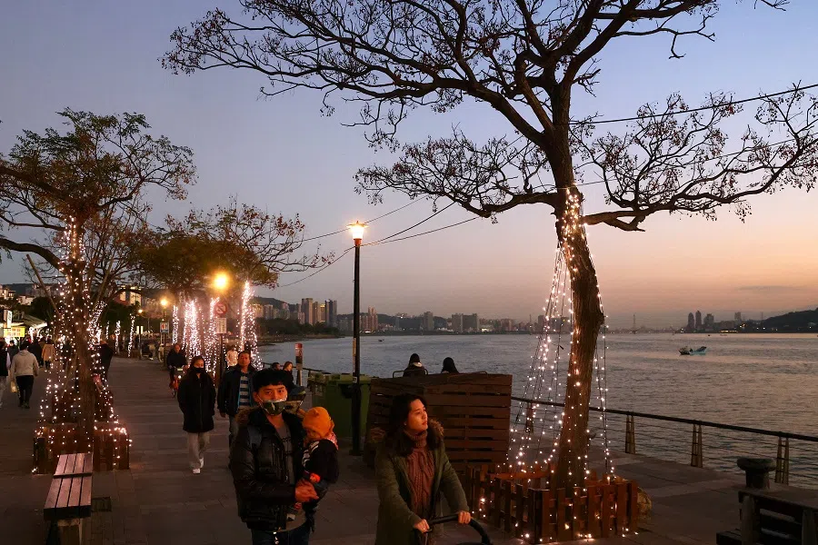 People wear protective masks while walking by the riverside in Taipei, Taiwan, 13 January 2021. (Ann Wang/Reuters)