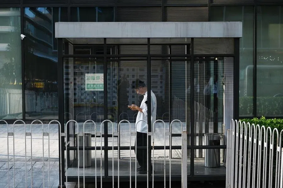 A man looks at his phone in a smoking area outside an office building in Beijing on 17 June 2026.