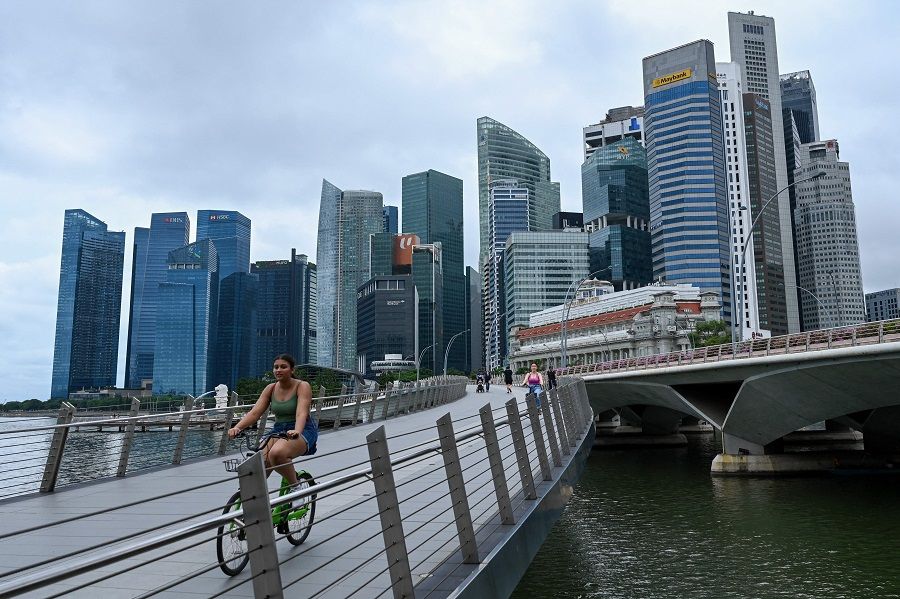 People ride bikes across a bridge next to the financial business district in Singapore on 7 April 2022. (Roslan Rahman/AFP)
