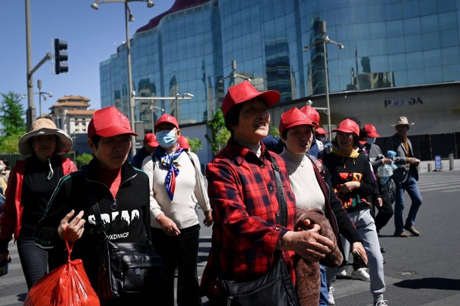 A group of tourists visits a business street in Beijing, China, on 18 April 2023. (Wang Zhao/AFP)