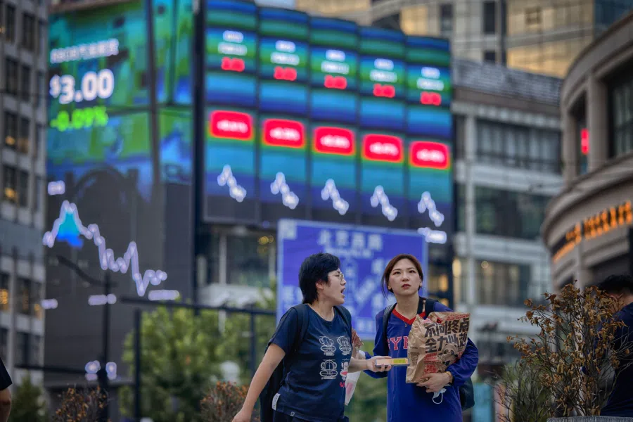 People walk in front of the large screen showing the latest stock exchange data, in Shanghai, China, 22 August 2022. (EPA-EFE/Alex Plavevski)