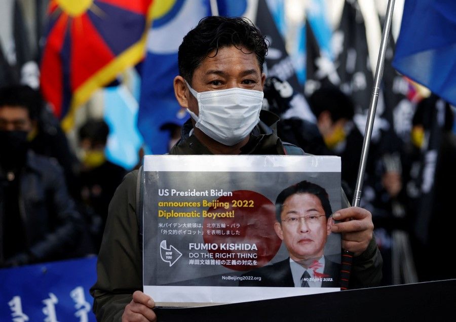 A protester displays a sign against the Beijing 2022 Winter Olympic Games during the Asia Peace March in observance of Human Rights Day, in Tokyo, Japan, 11 December 2021. (Issei Kato/Reuters)