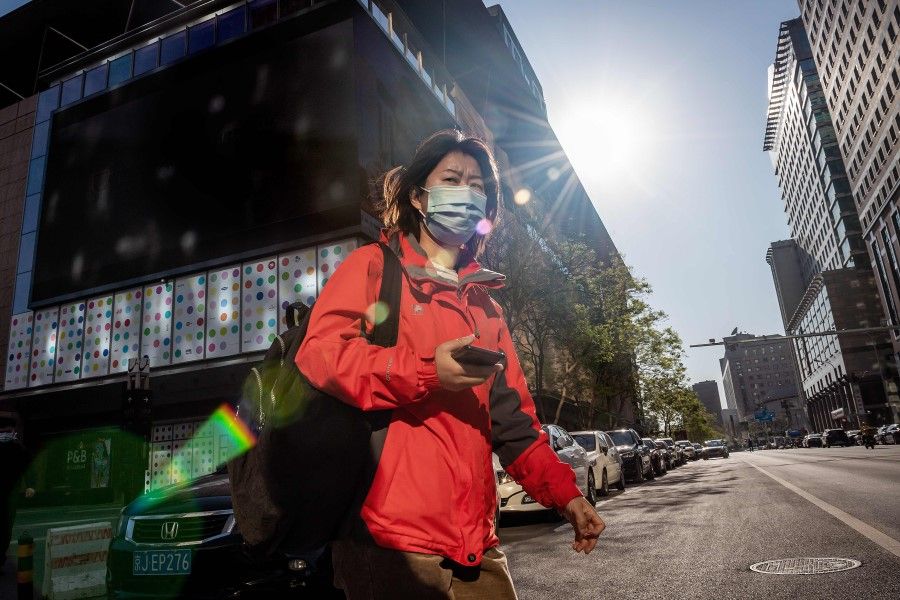 A woman crosses a street in Beijing, April 22, 2020. China's economy shrank for the first time in decades last quarter. (Nicolas Asfouri/AFP)