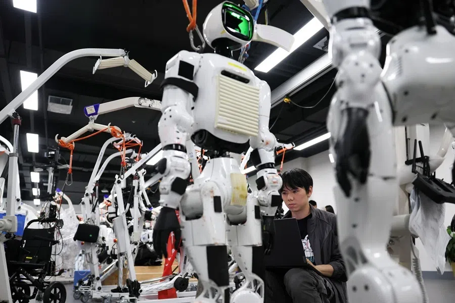 An engineer works near Tiangong Omni humanoid robots in the research and testing area of the Beijing Humanoid Robot Innovation Center, also known as X-Humanoid, in Beijing, China, 4 September 2026.
