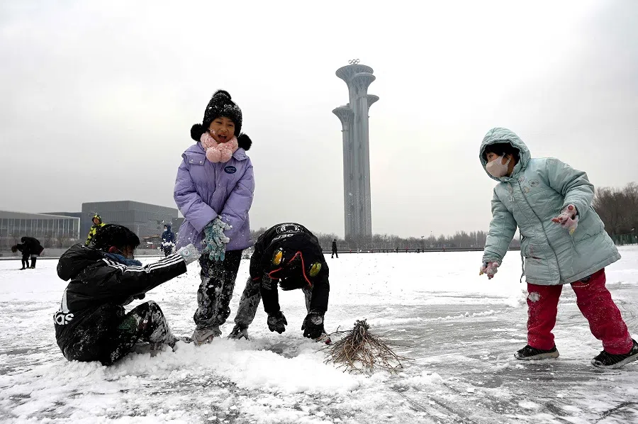 Children play in the snow on a frozen canal at the Beijing Olympic Park in Beijing, China, on 20 January 2022. (Noel Celis/AFP)