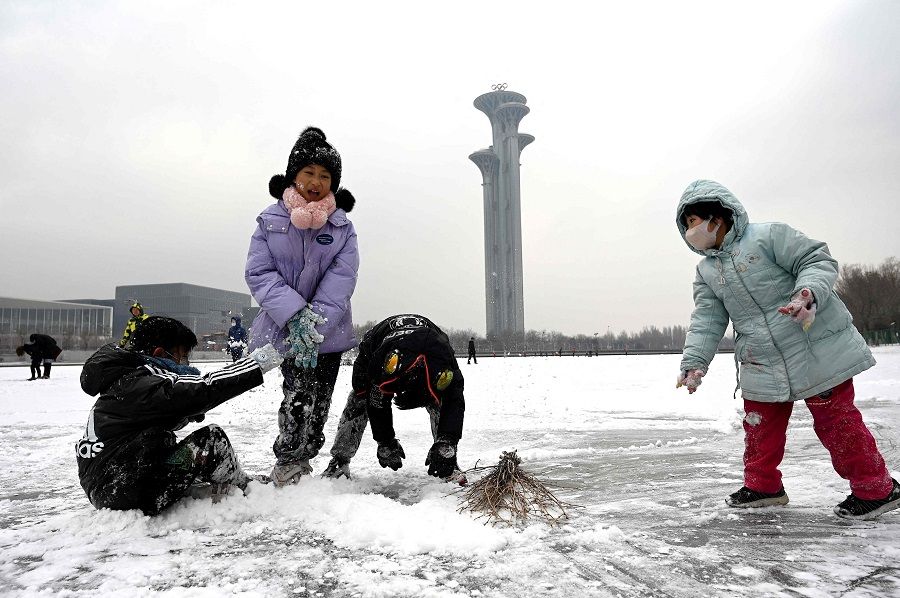 Children play in the snow on a frozen canal at the Beijing Olympic Park in Beijing, China, on 20 January 2022. (Noel Celis/AFP)