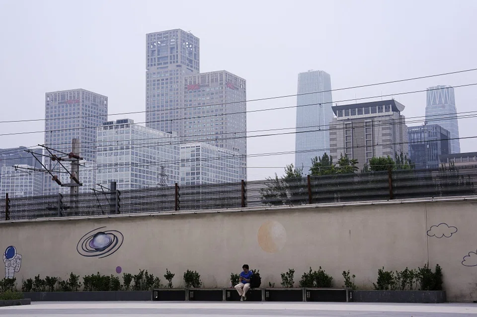 A person sits on a bench near Beijing’s Central Business District (CBD), China on 14 July 2024. (Tingshu Wang/Reuters)