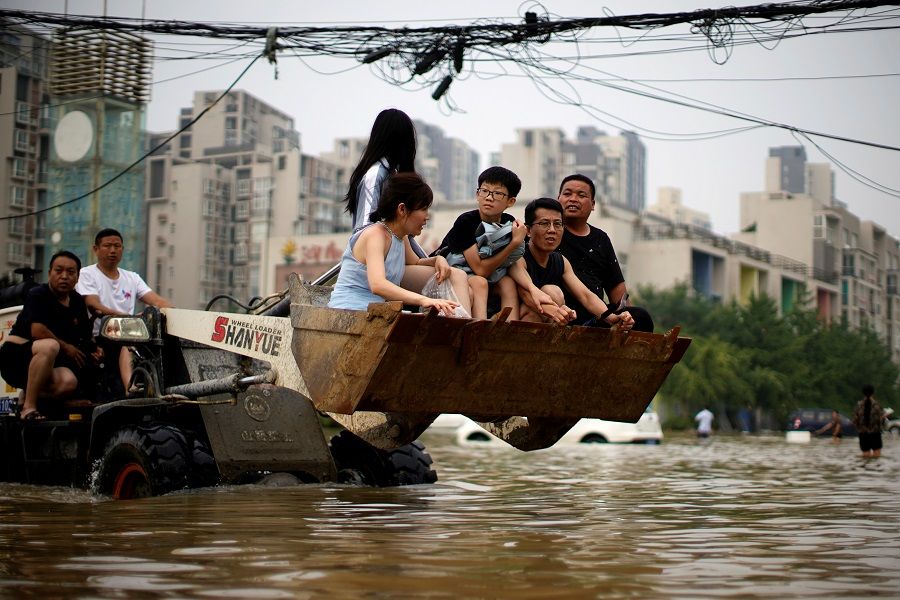 People ride on a front loader as they make their way through floodwaters following heavy rainfall in Zhengzhou, Henan province, China, 23 July 2021. (Aly Song/File Photo/Reuters)