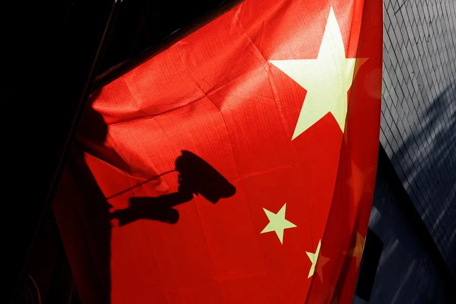 A surveillance camera is silhouetted behind a Chinese national flag in Beijing, China, on 3 November 2022. (Thomas Peter/Reuters)