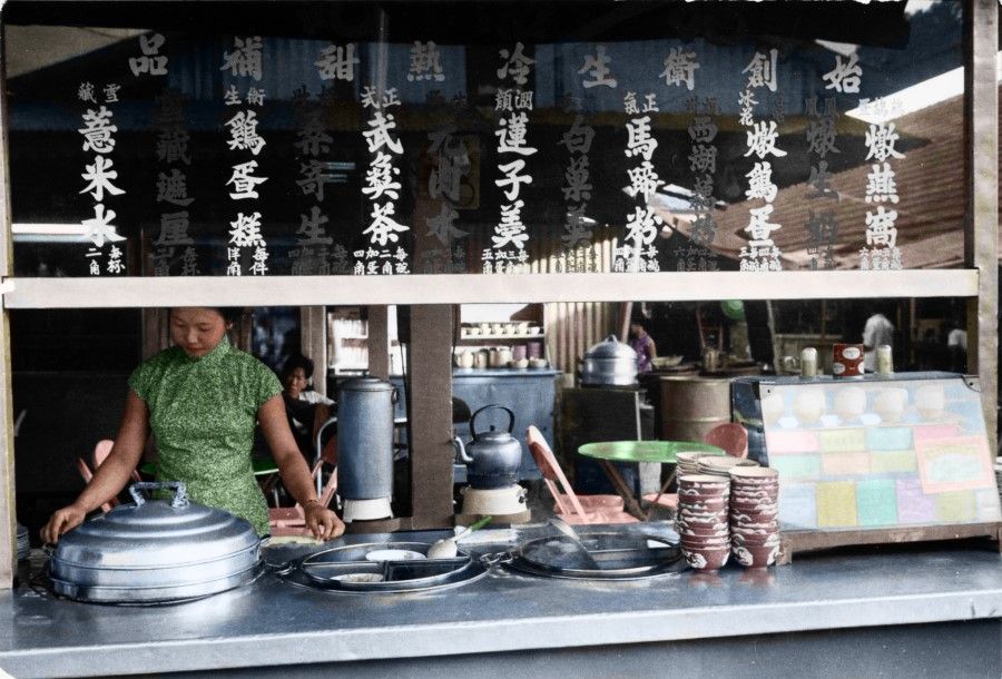 A stall in Singapore selling beverages and desserts in the 1960s. Its sign lists items such as lotus seed congee, water chestnut flour, barley water, and steamed sponge cake, which were all popular desserts at the time.
