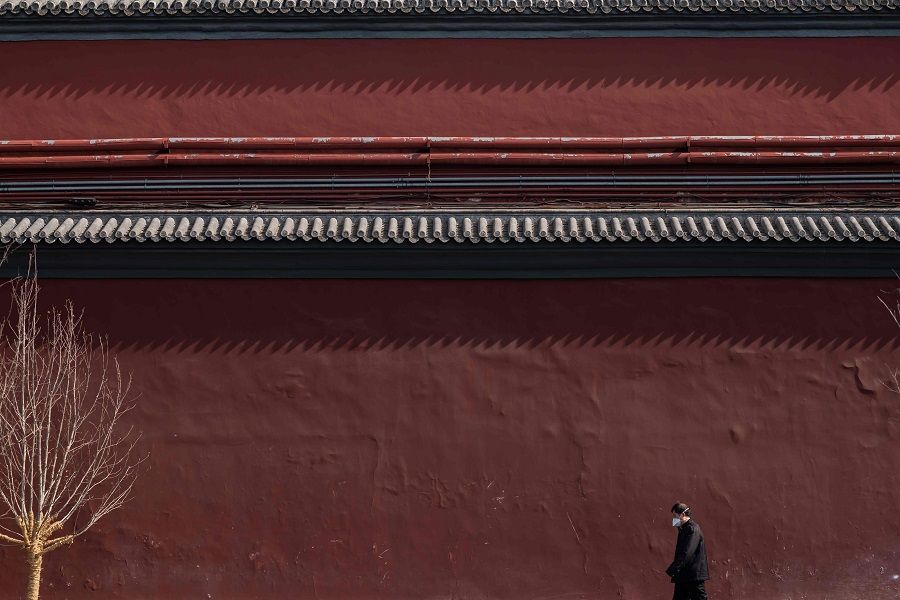 A man wearing a protective facemask to protect against the Covid-19 coronavirus walks outside the Lama Temple, which is closed due to coronavirus epidemic, in Beijing on 23 February 2020. (Nicolas Asfouri/AFP)
