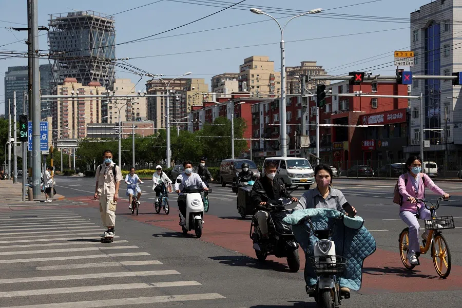 People wearing face masks ride vehicles on a road amid the Covid-19 outbreak in Beijing, China, 16 May 2022. (Tingshu Wang/Reuters)