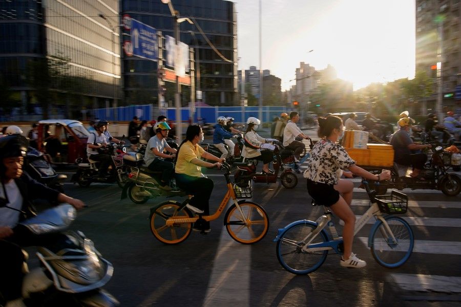 People ride bicycles and motorbikes on a street in Shanghai, China, 31 May 2021. (Aly Song/Reuters)