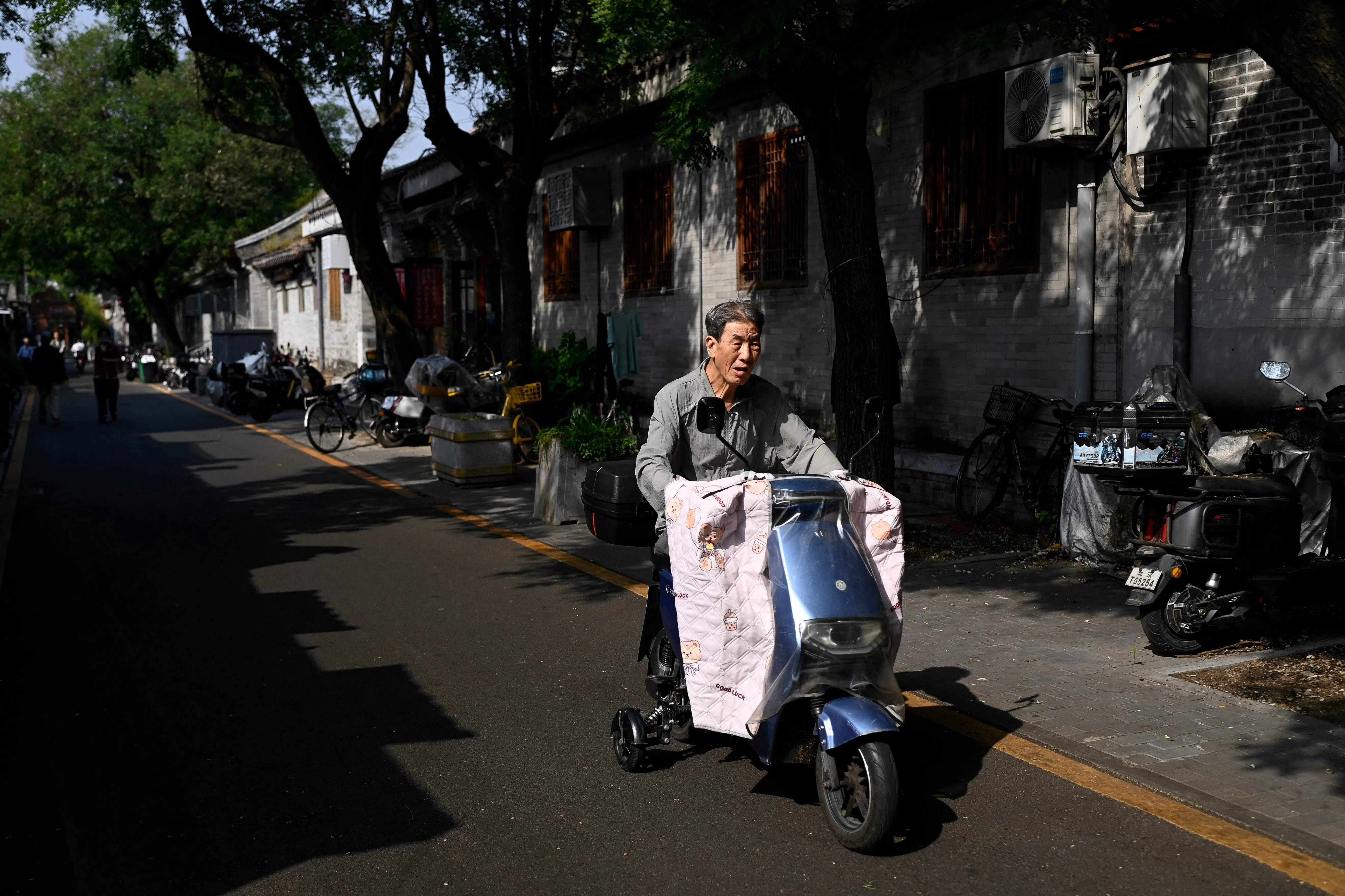 An elderly man rides a electric scooter through an alley in Beijing on 29 September 2026.