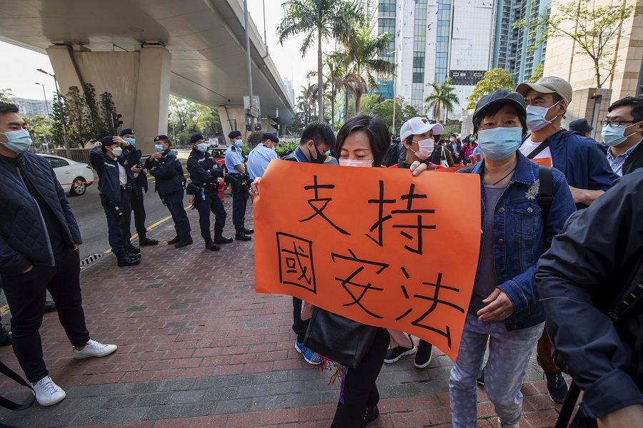 A pro-government demonstrator holds a placard reading "Support national security law" outside the West Kowloon Magistrates' Courts ahead of a hearing for 47 opposition activists charged with violating the city's national security legislation in Hong Kong, China, on 1 March 2021. (Paul Yeung/Bloomberg)