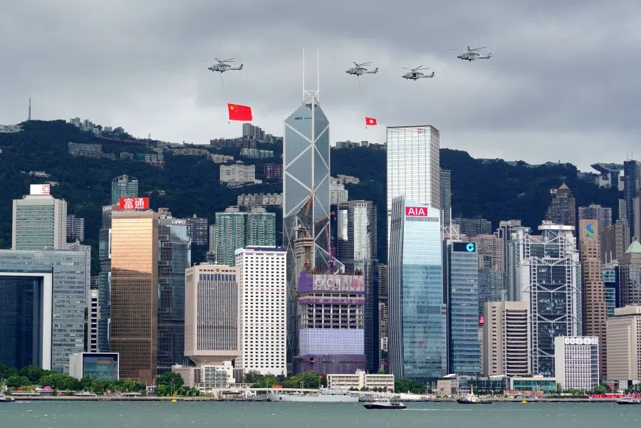 Helicopters carrying Chinese and Hong Kong flags fly over the Victoria Harbour during a flag-raising ceremony at the Golden Bauhinia Square, on the 25th anniversary of the former British colony's handover to Chinese rule, in Hong Kong, China, 1 July 2022. (CNS via Reuters)