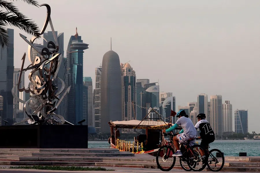 People walk next to an anchored traditional dhow boat are in front of the Doha skyline on 5 July 2025. (Karim Jaafar/AFP)