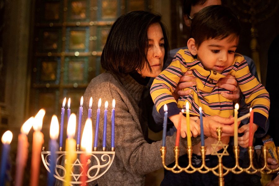 People light a Hanukkah candle before participating in a Shabbat service in Philadelphia, Pennsylvania, US, 23 December 2022. (Hannah Beier/Reuters)