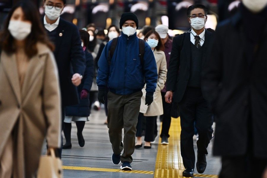 Mask-clad commuters make their way to work during morning rush hour at the Shinagawa train station in Tokyo. (Charly Triballeau/AFP)