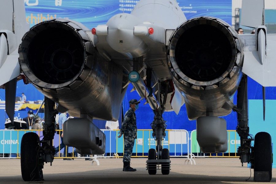 A military personnel stands under a People's Liberation Army Air Force (PLAAF) aircraft at the 13th China International Aviation and Aerospace Exhibition in Zhuhai in southern China's Guangdong province on 28 September 2021. (Noel Celis/AFP)