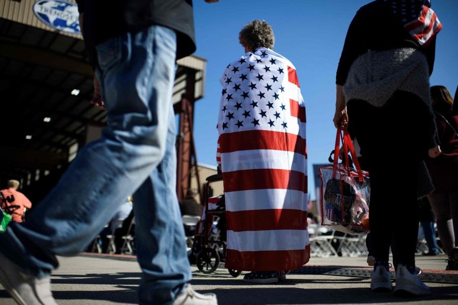 An attendee is draped in an American flag before a rally of former US president and 2024 presidential hopeful Donald Trump in Houston, Texas, on 2 November 2023. (Mark Felix/AFP)
