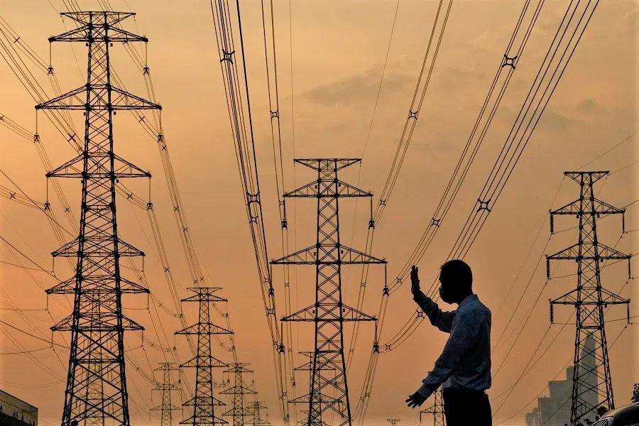 A parking assistant gestures as he stands below power lines in Beijing, China, on 13 October 2021. (Noel Celis/AFP)
