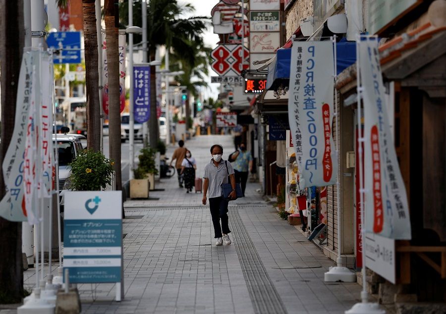 People wearing protective face masks walk along Kokusai-dori, in Naha, Okinawa prefecture, Japan, 25 October 2021. (Issei Kato/Reuters)