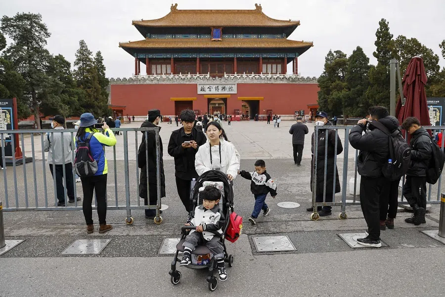 People stroll on a street near the Forbidden City in Beijing, China, on 5 April 2023. (Ludovic Marin/AFP)