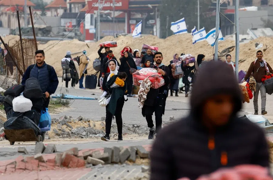Israeli flags flutter as Palestinians fleeing Khan Younis, due to the Israeli ground operation, move towards Rafah, amid the ongoing conflict between Israel and the Palestinian Islamist group Hamas, in the southern Gaza Strip, on 28 January 2024. (Ibraheem Abu Mustafa/Reuters)
