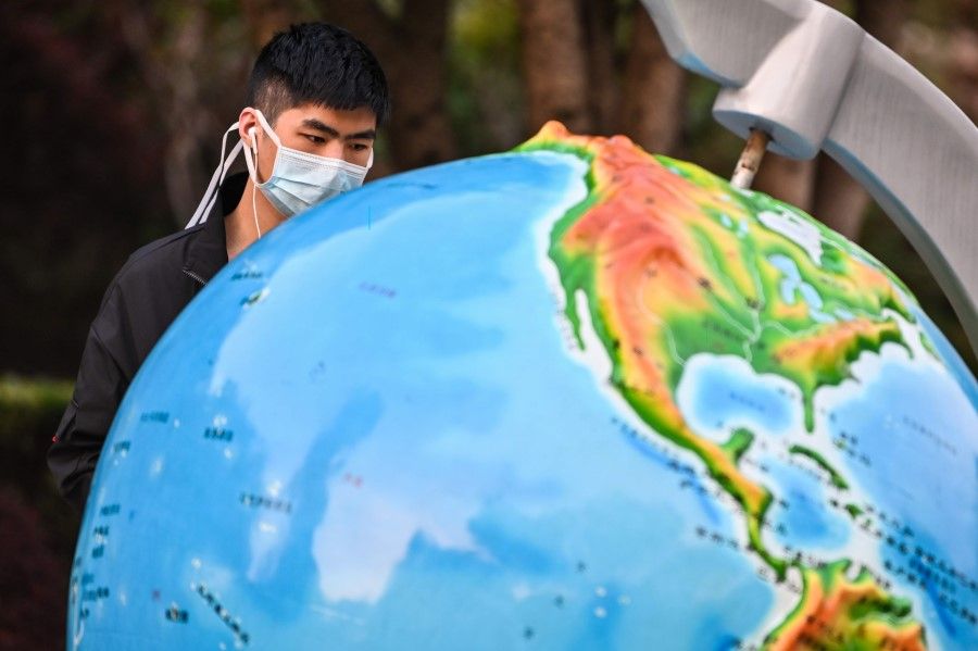 A man looks at a globe in a park in Wuhan, 8 April 2020. (Hector Retamal/AFP)