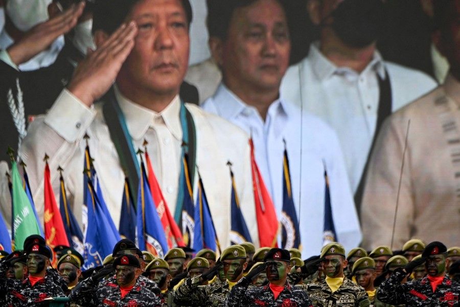 Philippine President Ferdinand Marcos Jr. (centre) is seen on a video screen as he salutes in front of the troops during the 87th anniversary celebration of the Armed Forces of the Philippines, at the military headquarters in Quezon City in suburban Manila on 19 December 2022. (Ted Aljibe/AFP)