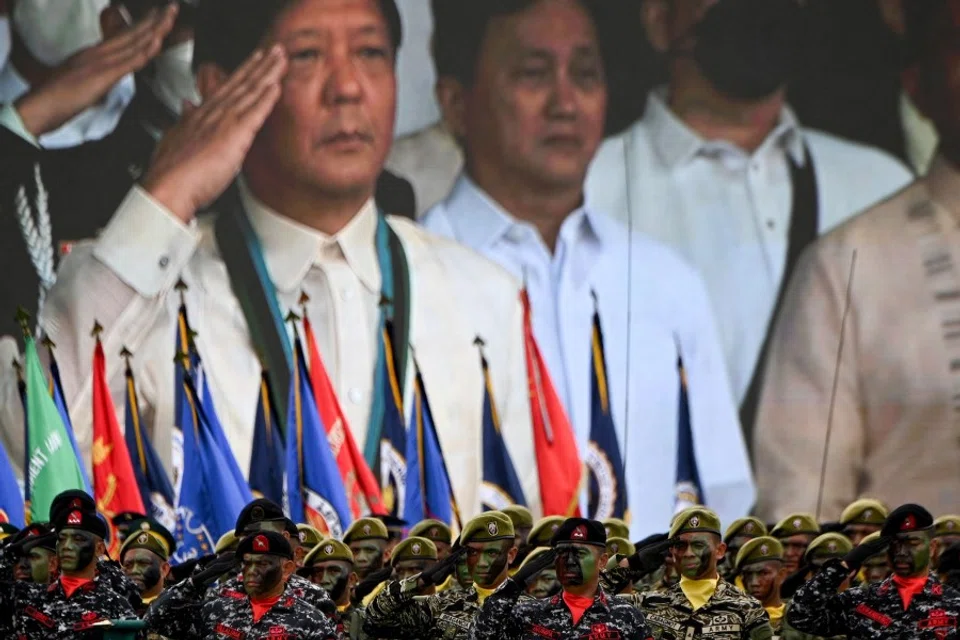 Philippine President Ferdinand Marcos Jr. (centre) is seen on a video screen as he salutes in front of the troops during the 87th anniversary celebration of the Armed Forces of the Philippines, at the military headquarters in Quezon City in suburban Manila on 19 December 2022. (Ted Aljibe/AFP)