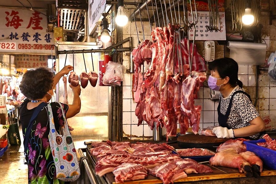 A woman buys pork at a market in Taipei, Taiwan, 4 August 2022. (Ann Wang/Reuters)