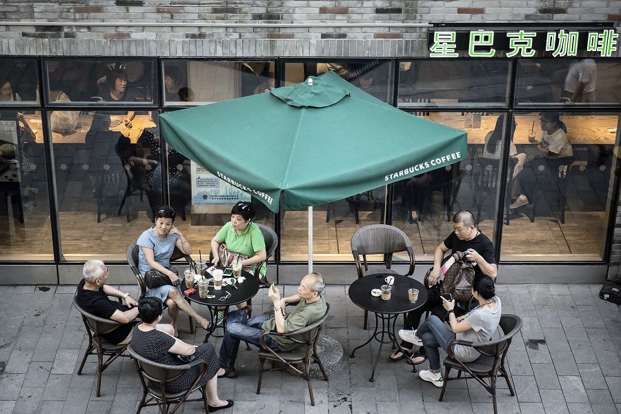 Customers sit at outdoor tables at a Starbucks Corp. coffee shop in Shanghai, China, on 6 August 2016. (Qilai Shen/Bloomberg)