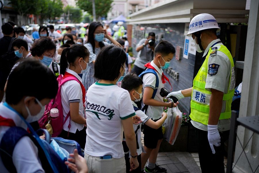 A security guard measures the body temperature of a student entering a school, as schools reopen following months of closure since the Covid-19 outbreak in Shanghai, China, 1 September 2022. (Aly Song/Reuters)