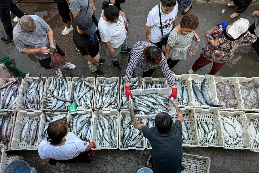 People shop for fish at a market in Shenyang, Liaoning province, China, on 9 September 2024. (AFP)