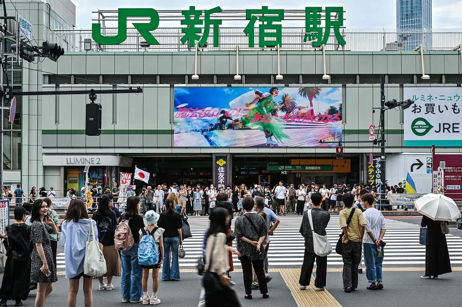 This photo taken on 30 June 2024 shows people waiting to cross the street outside the south entrance to Shinjuku station, in Tokyo. (Richard A. Brooks/AFP)
