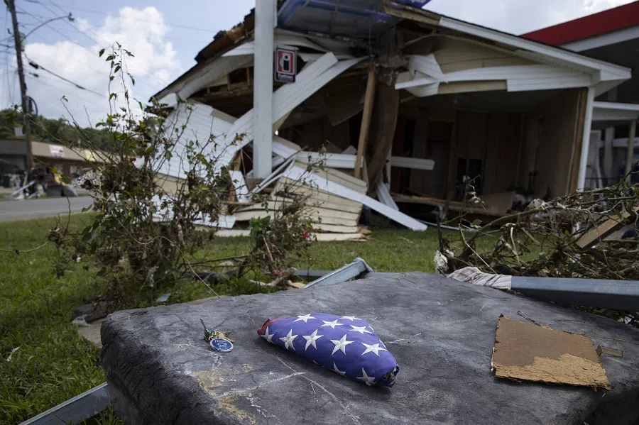 An American flag sits folded on its former flagpole base alongside a set of lost keys with a religious message on 23 August 2021 in Waverly, Tennessee. (Brett Carlsen/Getty Images/AFP)
