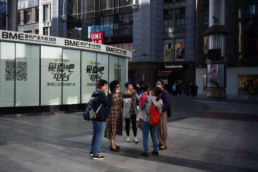 A group of women chat outside a shopping mall in Beijing on 17 September 2020. A Uniqlo logo can be seen in the background. (Greg Baker/AFP)