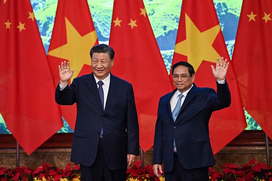 Vietnam's Prime Minister Pham Minh Chinh (right) and the China's President Xi Jinping (left) wave to the media during their meeting at the Government Office in Hanoi on 13 December 2023. (Nhac Nguyen/AFP)