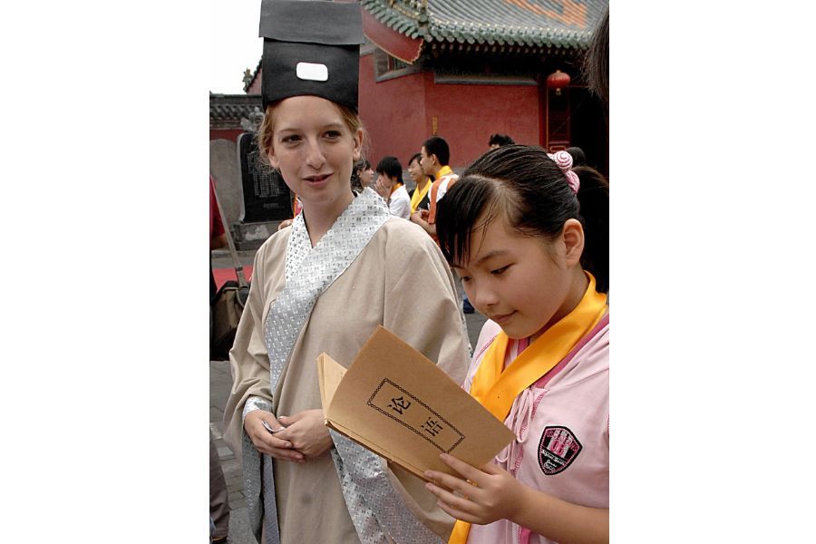 An American college student in traditional Chinese costume with a Chinese student reading the Analects of Confucius at Wen Temple in Zhengzhou, China. However, in recent years, Confucius Institutes have encountered barriers and even been stigmatised in the US and other countries. (Xinhua)